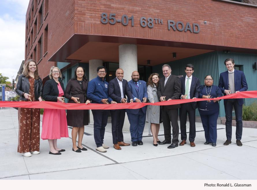 Group photo of people standing in front of a building to cut a ribbon commemorating the opening of  Woodhaven ELLA affordable housing 