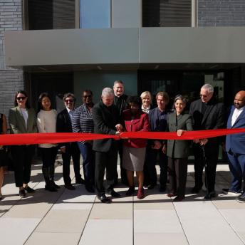 public and private partners cutting the ribbon on on a new affordable housing development, standing in a line. 